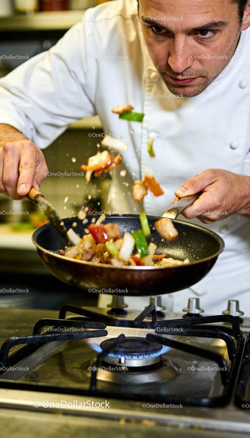 Chef Tossing Stir-Fry Vegetables Over Gas Stove