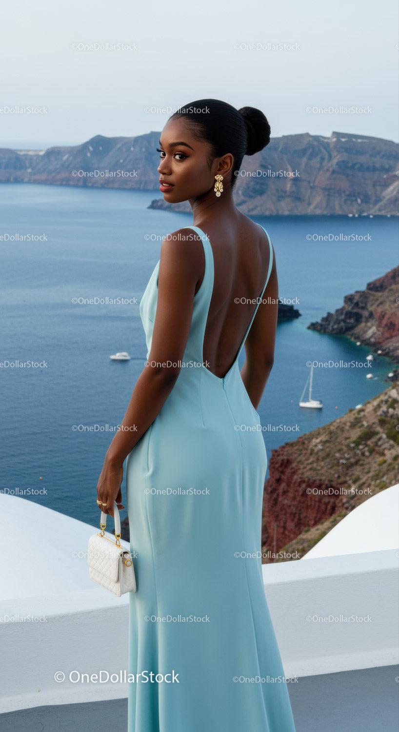 Elegant woman in light blue gown overlooking sea cliffs