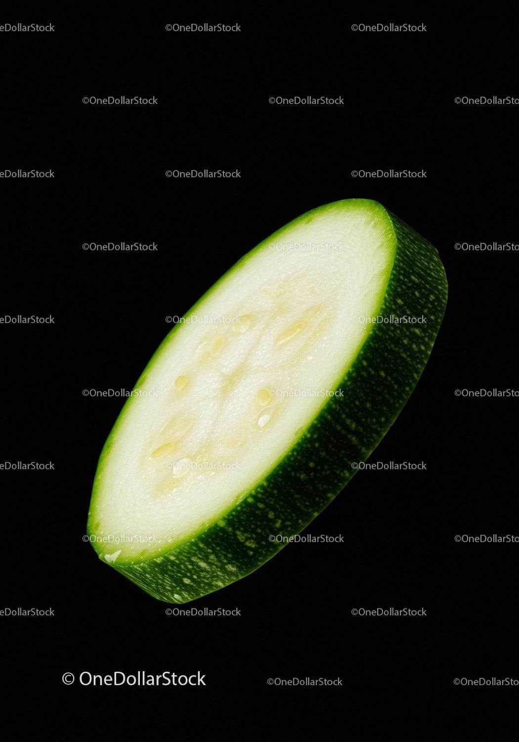 Close-up of fresh green zucchini slice on black
