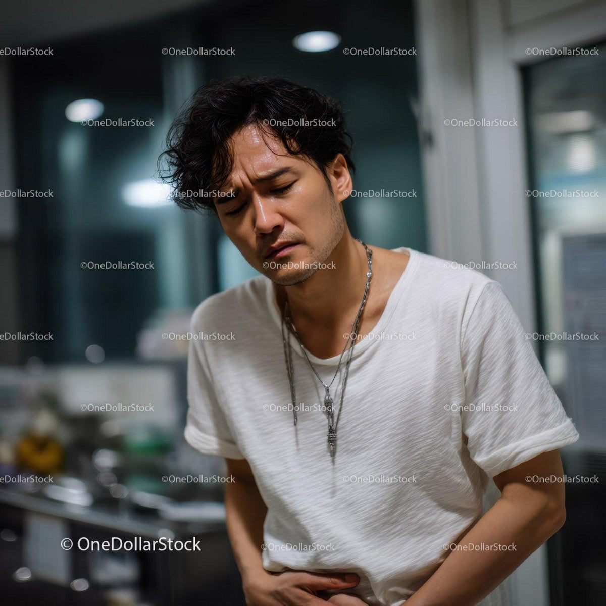 Young Man Experiencing Stomach Pain in Modern Indoor Setting