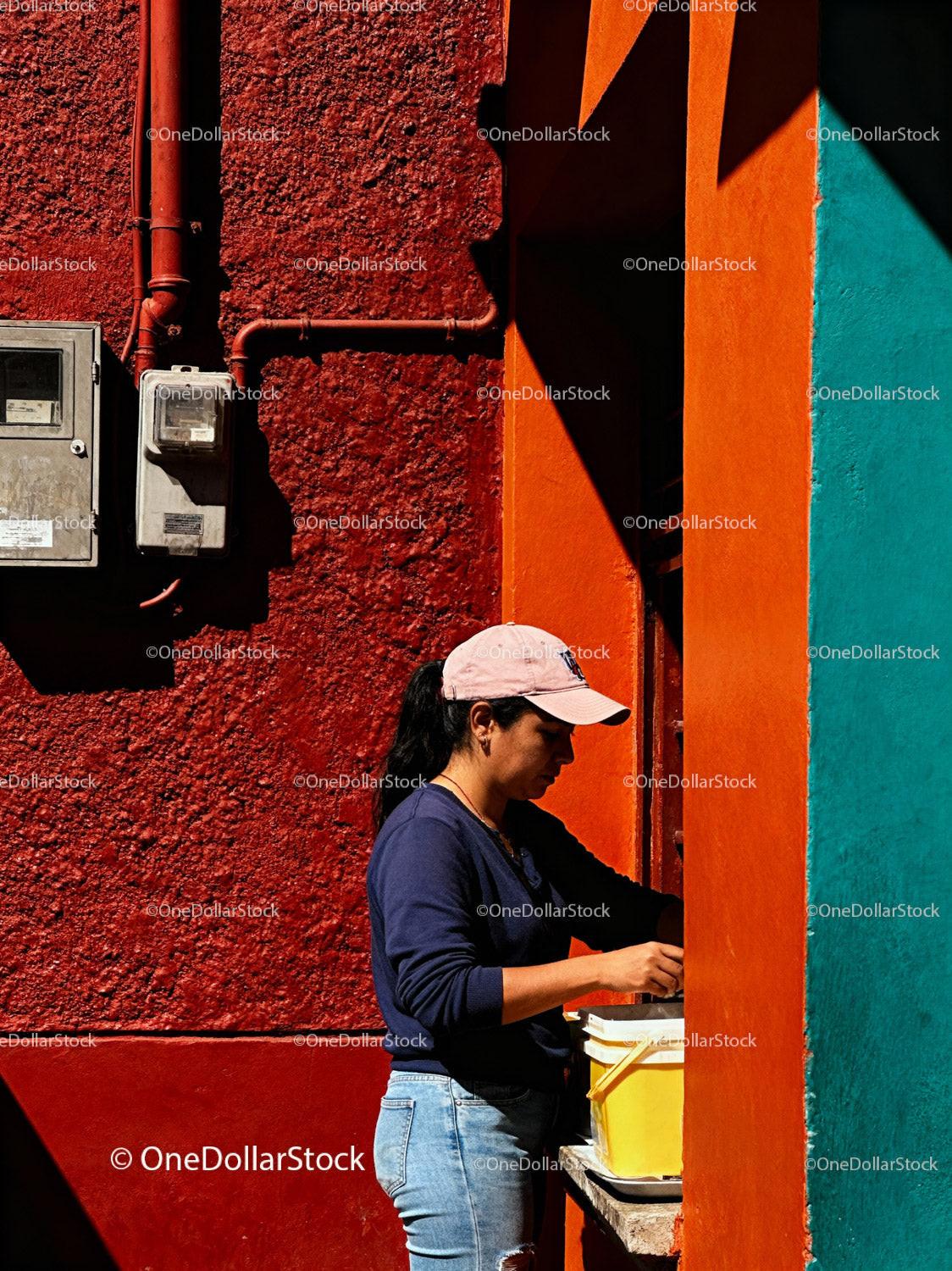 Woman Preparing Food Outside Colorful Urban Wall