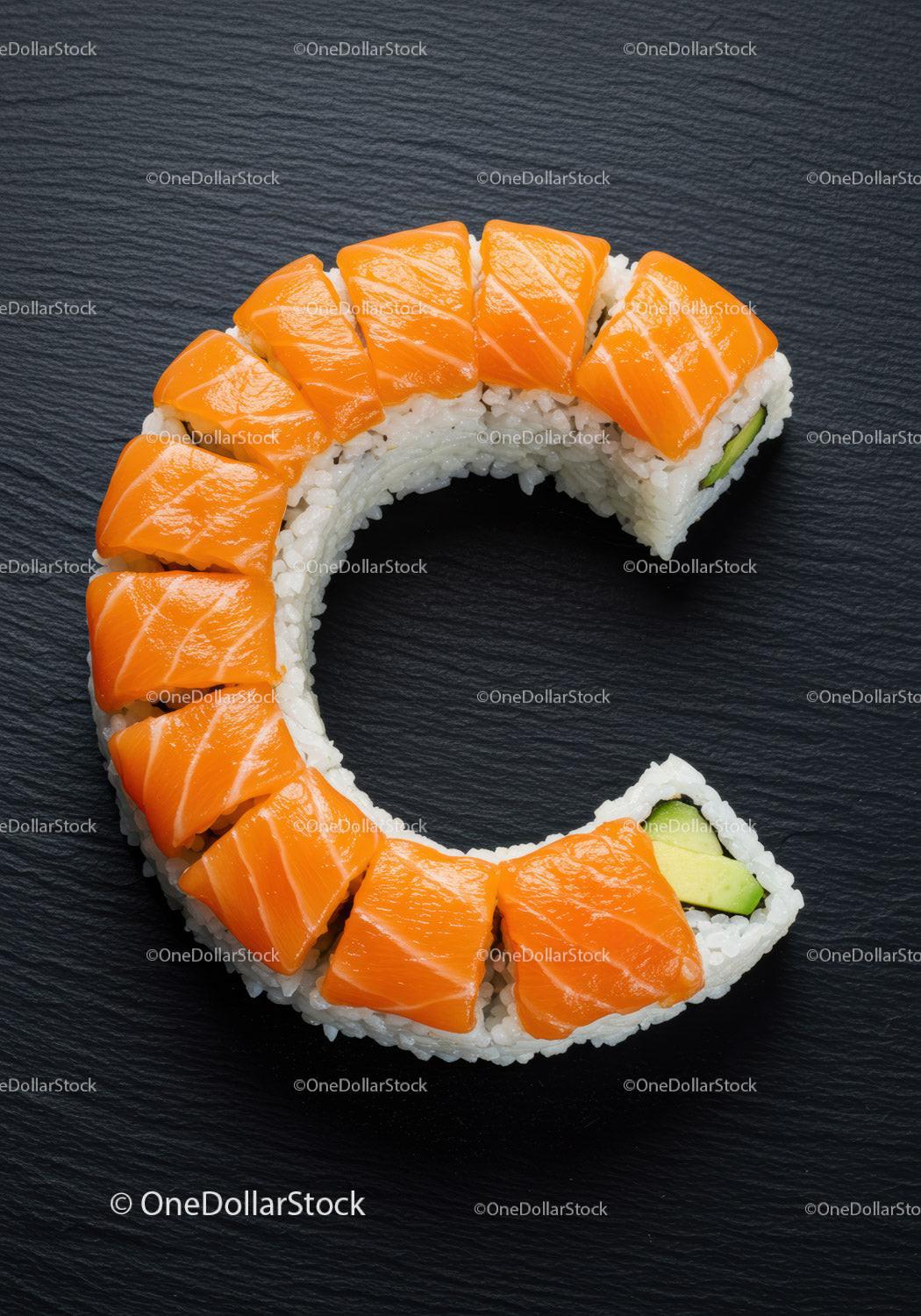 Fresh salmon sushi roll arranged in C shape on black slate