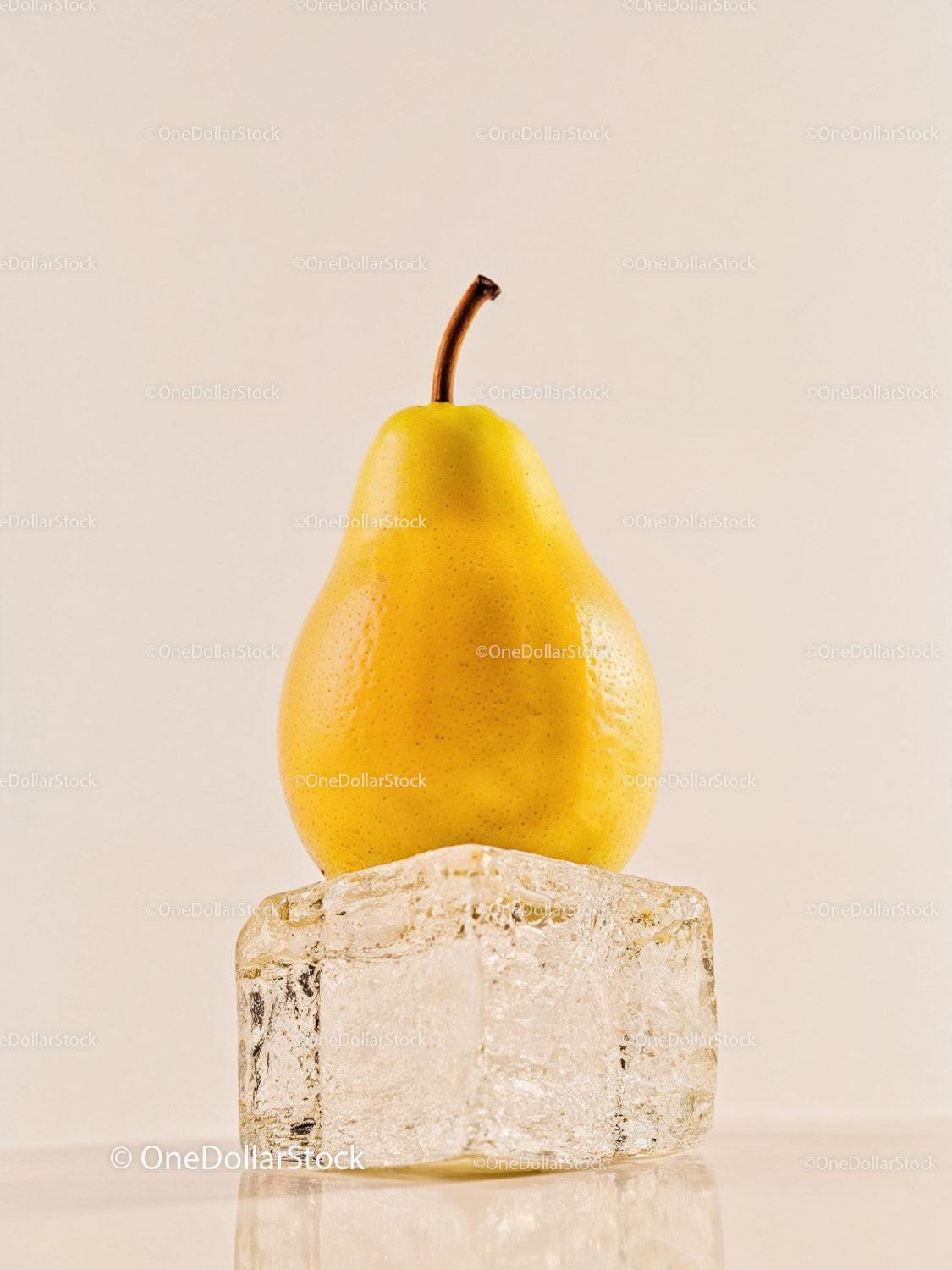 Yellow pear balanced on a clear ice cube