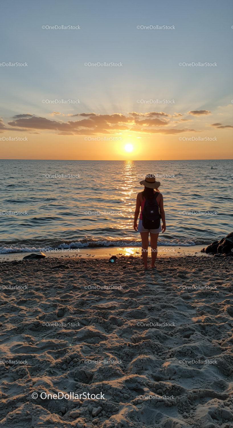 Woman enjoying peaceful sunset at calm sandy beach