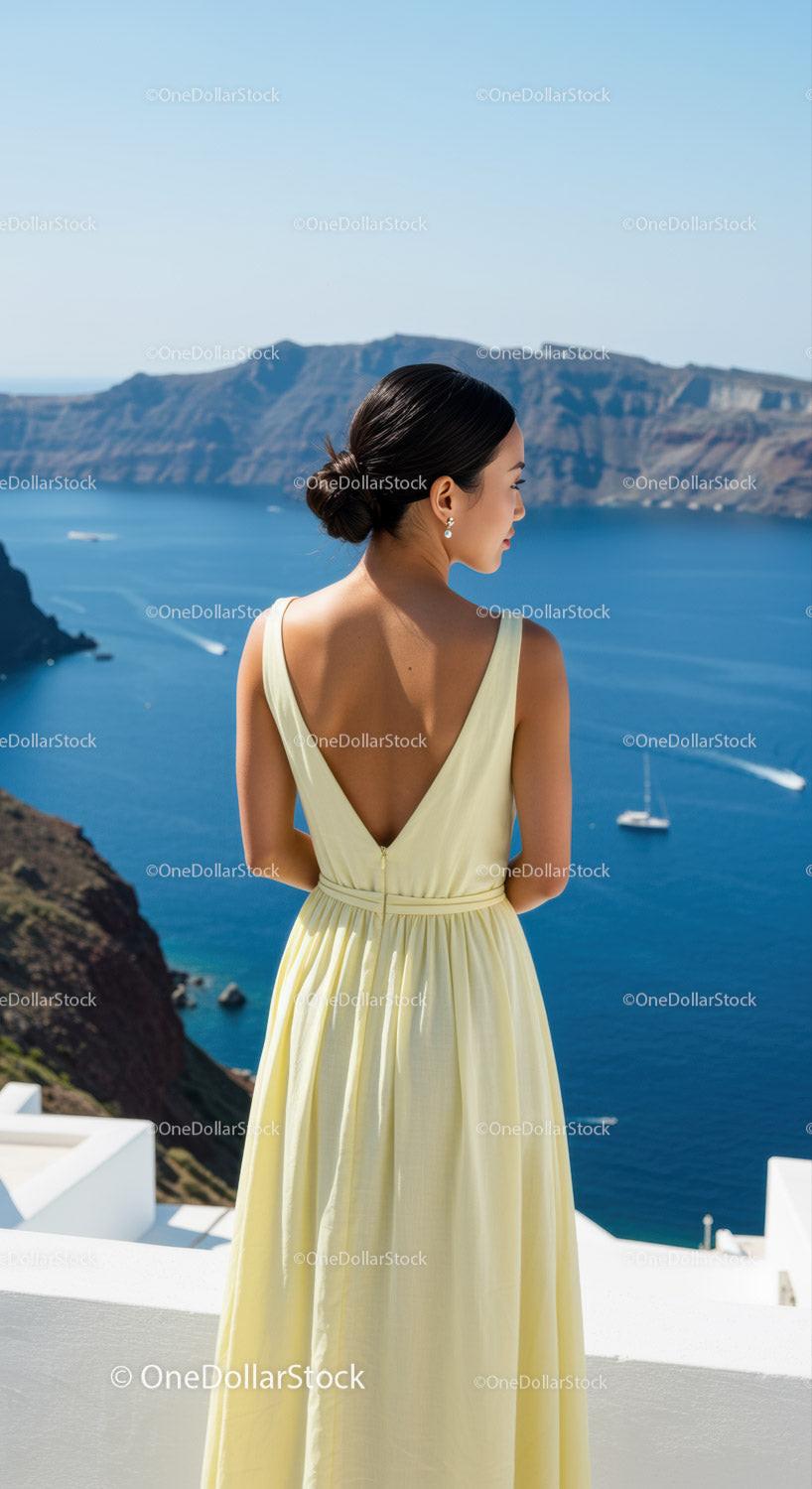 Woman in elegant dress overlooking blue sea and cliffs