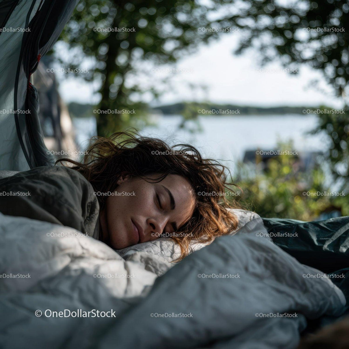 Peaceful outdoor scene of a woman sleeping by a lakeside beneath lush green trees