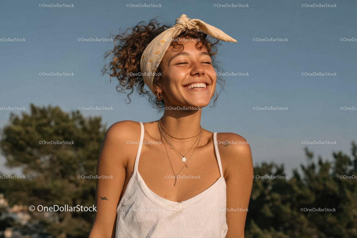 Joyful Young Woman with Curly Hair and Headband in Sunlit Outdoors