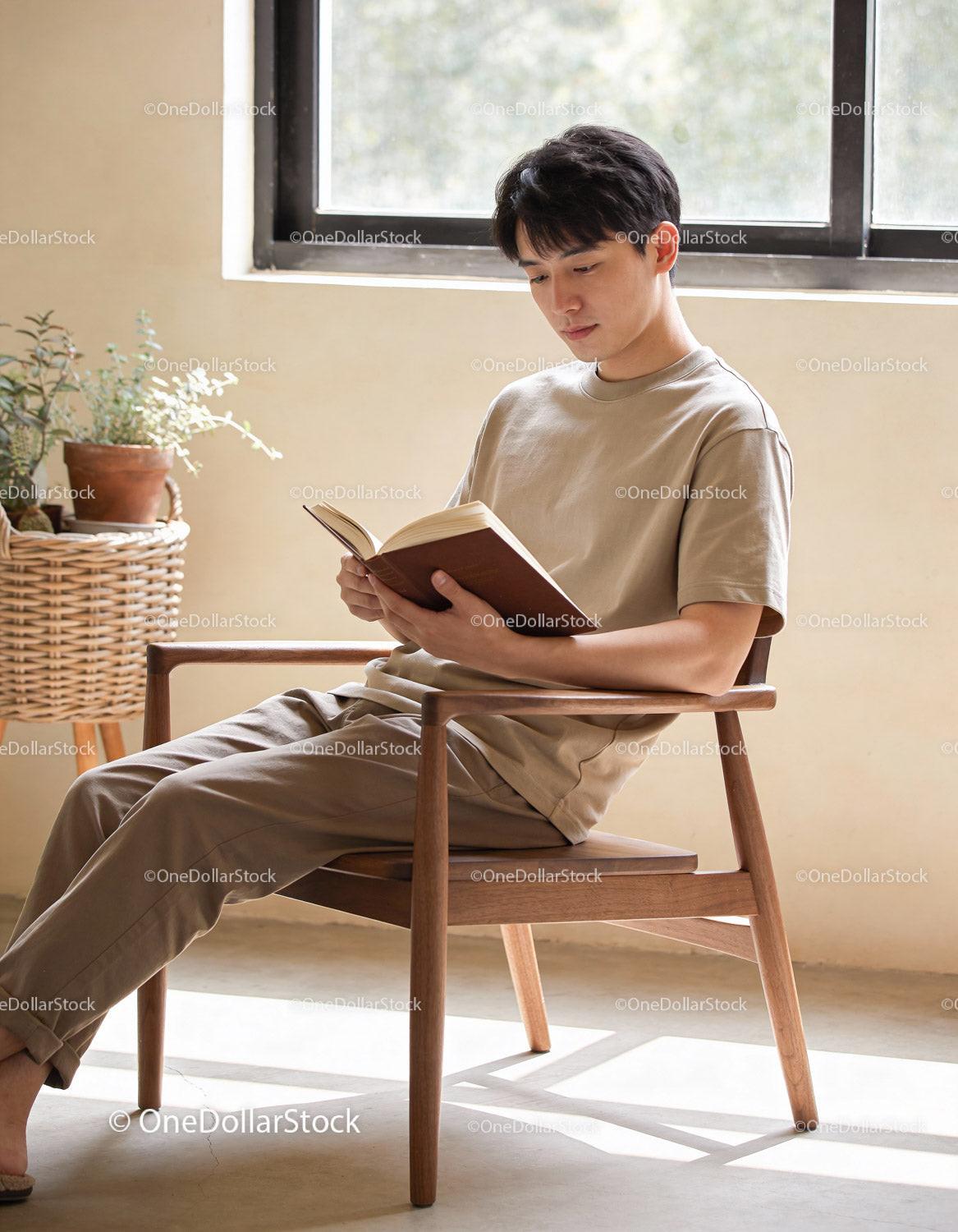 Young man reading book in bright serene room