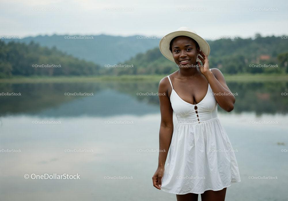 Joyful Woman in White Sundress and Straw Hat by Lake Outdoors