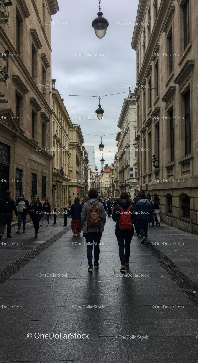 People Walking Along Historic City Street with Overcast Sky