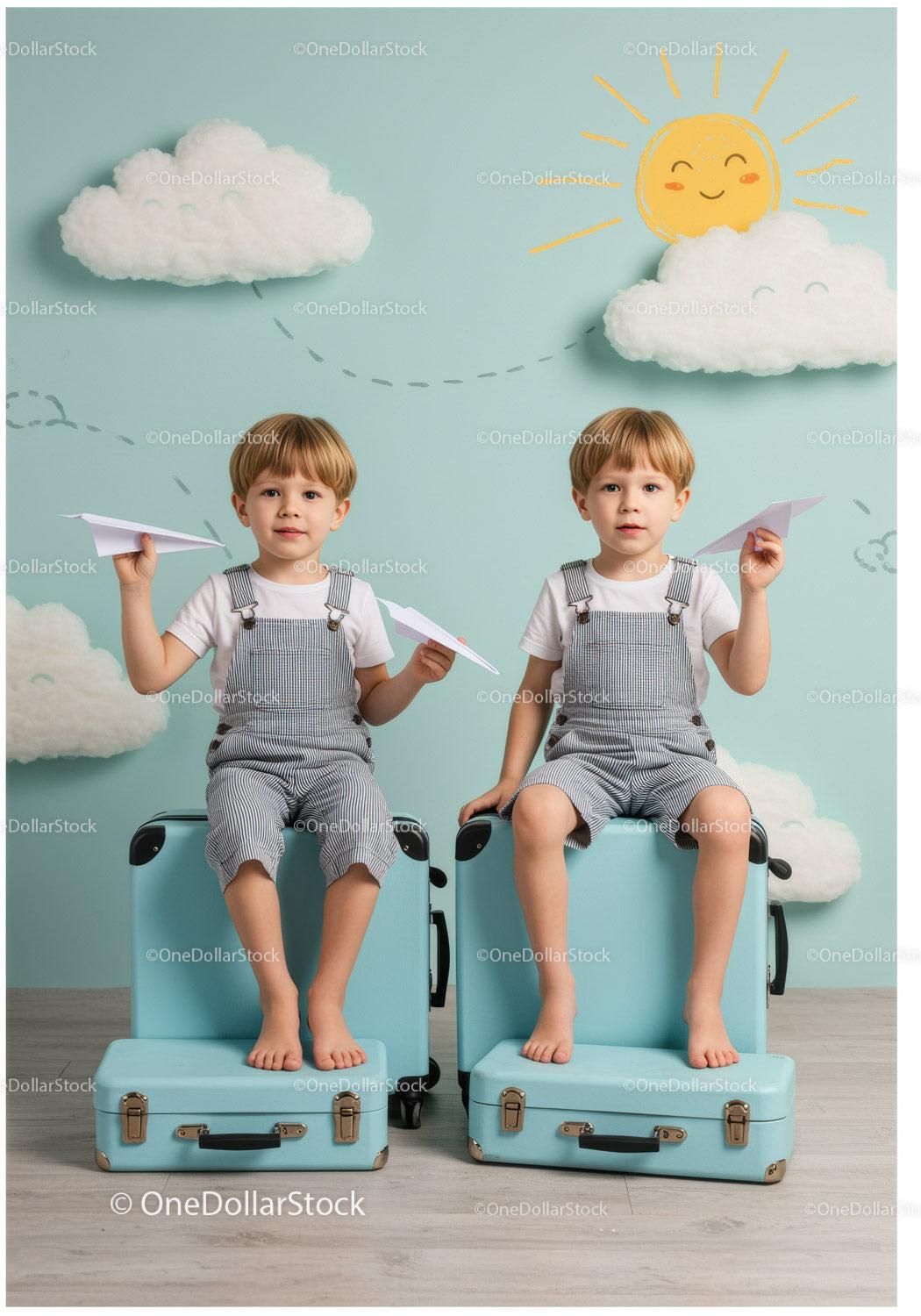 Twin boys sitting on suitcases with paper planes