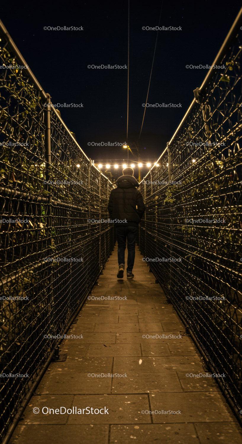 Person walking through narrow illuminated pathway at night