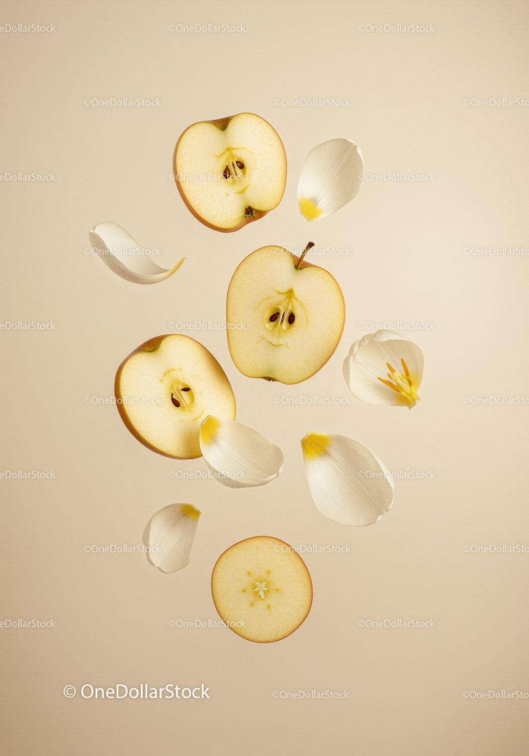 Fresh apple slices with scattered white flower petals