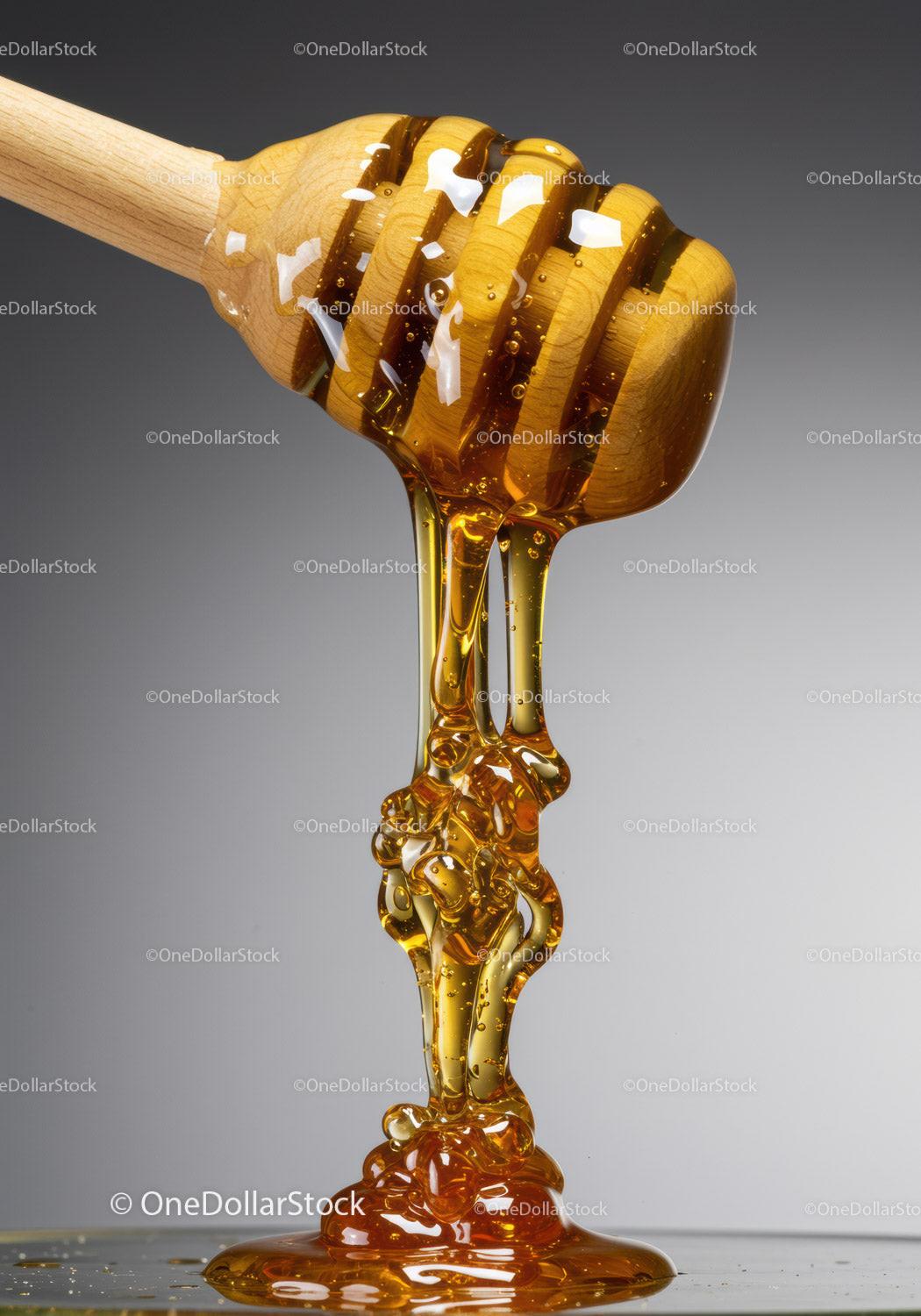 Golden honey dripping from wooden dipper on gray background
