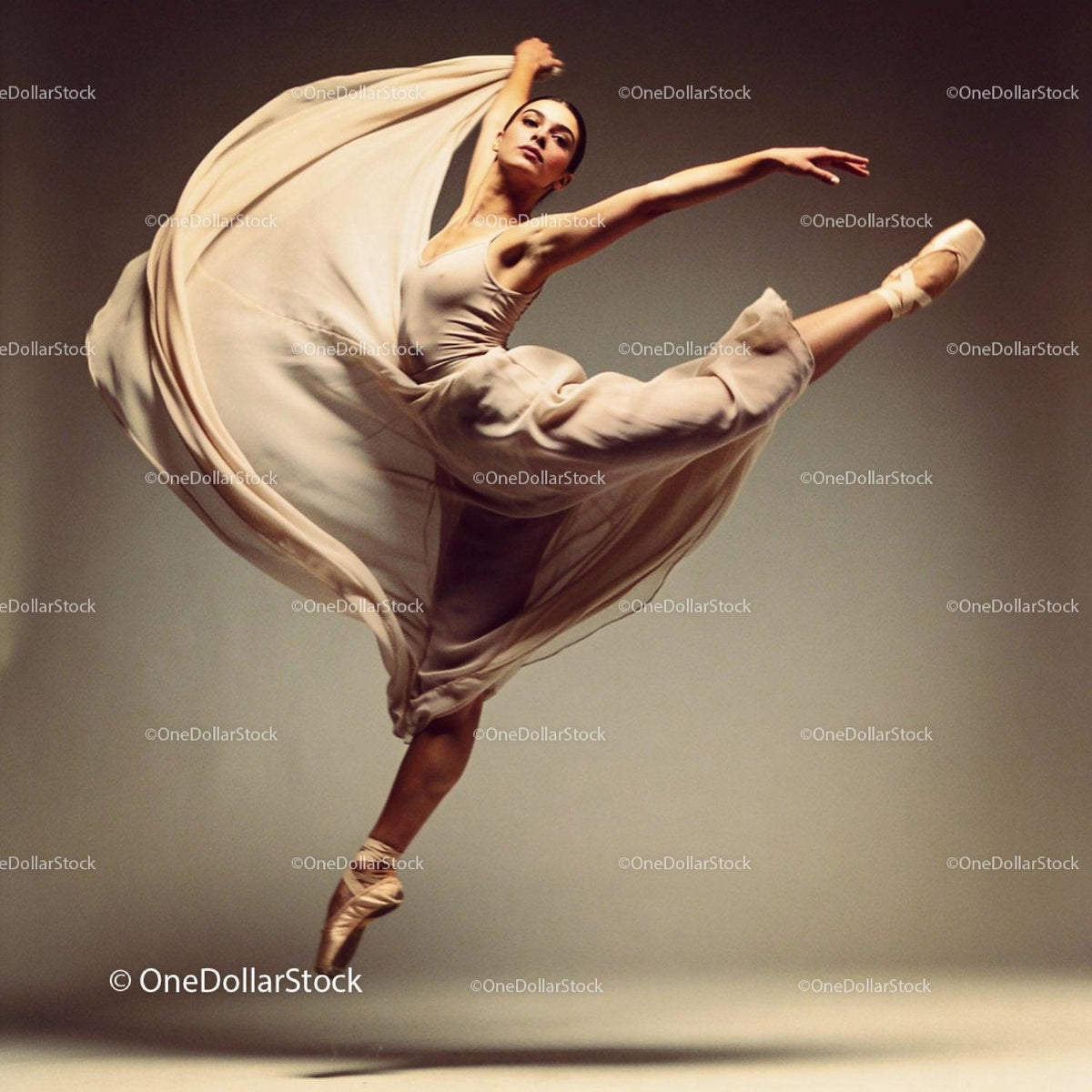 Graceful ballerina leaping in flowing beige dress