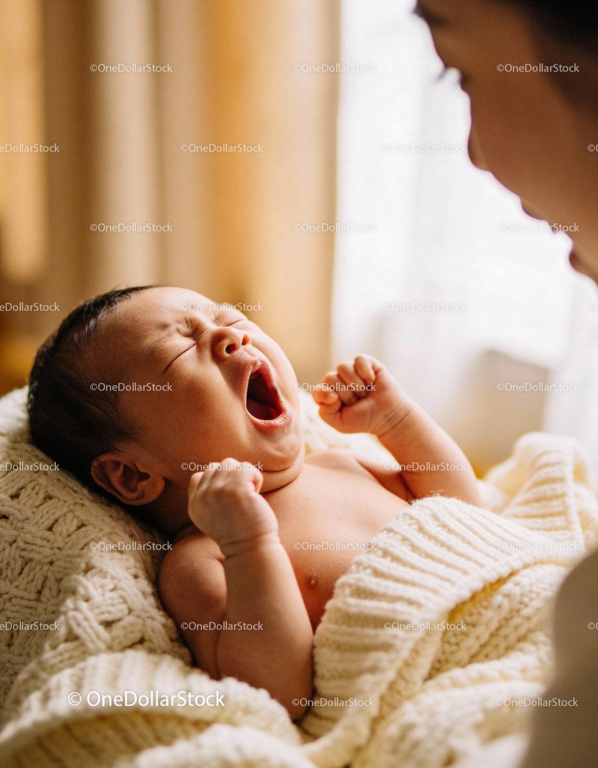 Yawning newborn baby wrapped in cozy knit blanket