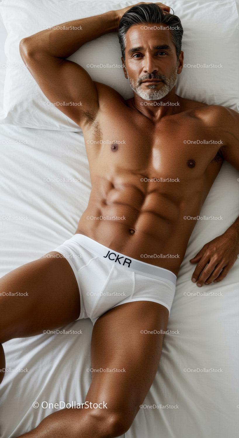 Fit mature man relaxing on bed in white briefs