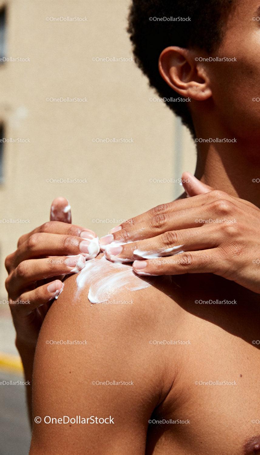 Person gently applying moisturizing cream on shoulder
