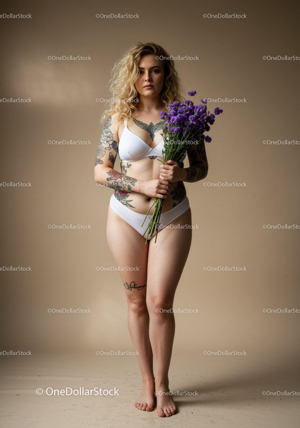 Tattooed Woman in White Lingerie Holding Purple Flowers in Studio