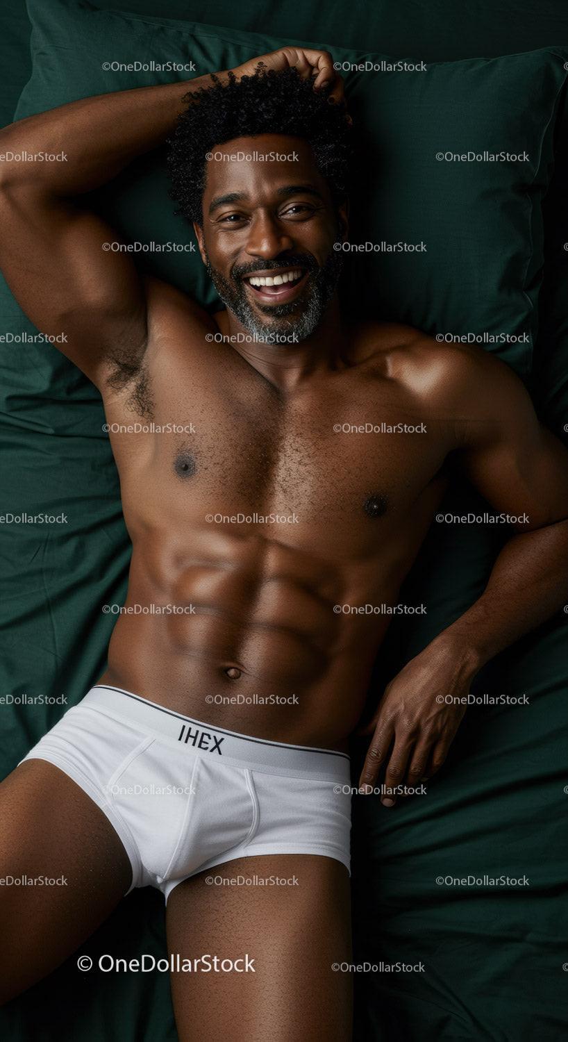 Smiling muscular man relaxing on dark green bedding