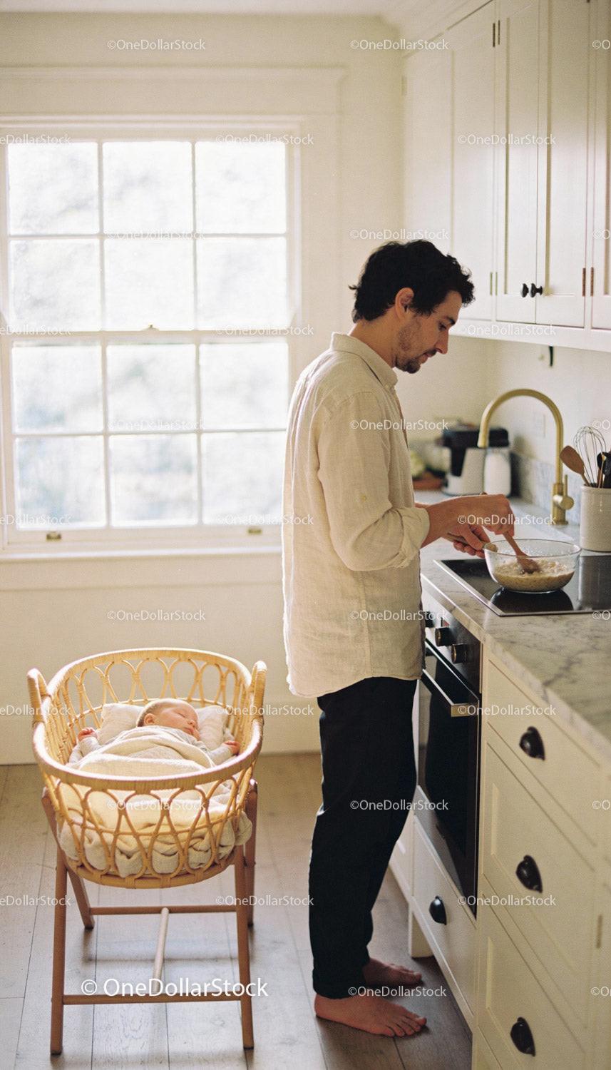 Father Preparing Breakfast While Baby Sleeps Nearby