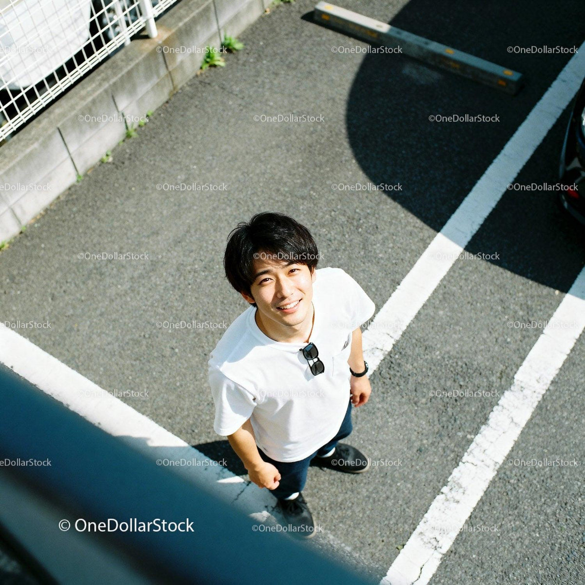 Young man smiling outdoors in sunny parking lot