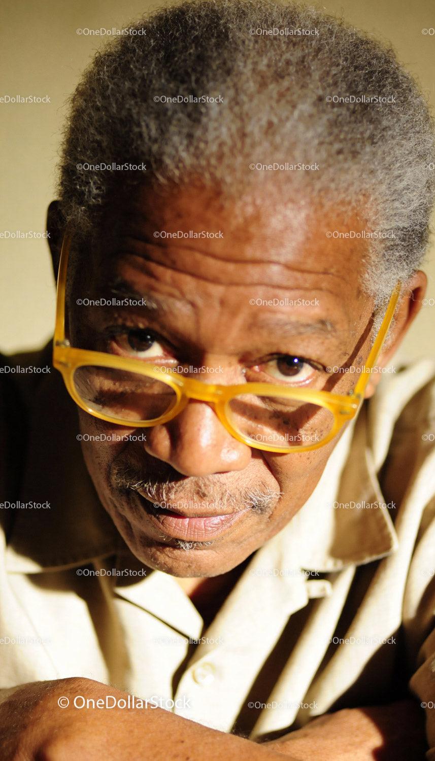 Elderly man with yellow glasses in thoughtful pose