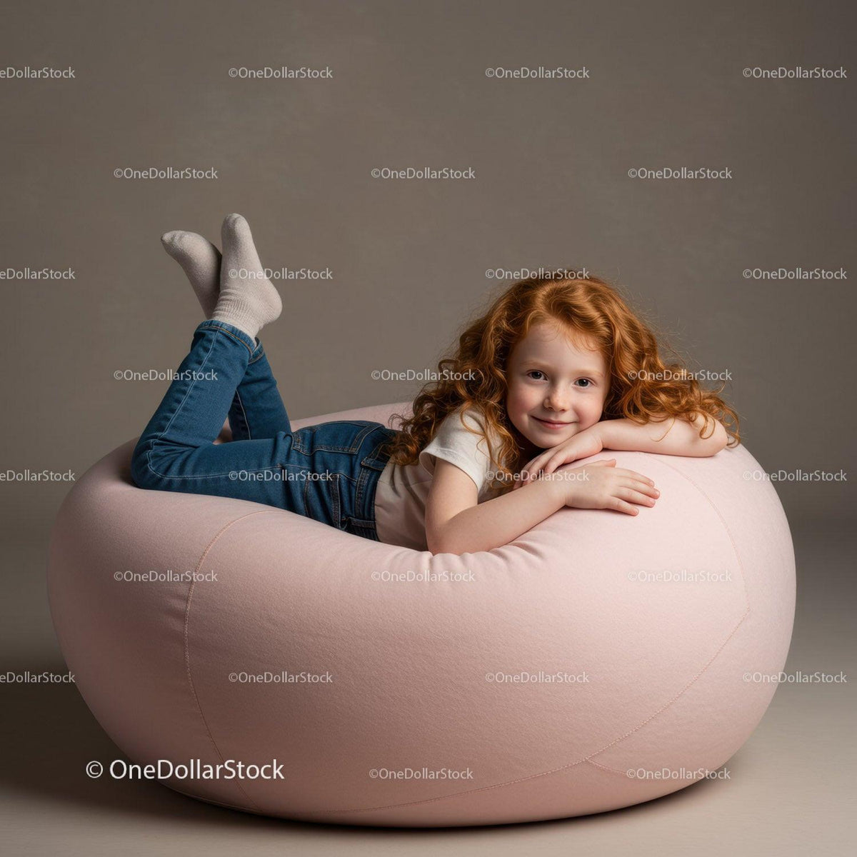 Smiling redhead girl relaxing on soft pink bean bag