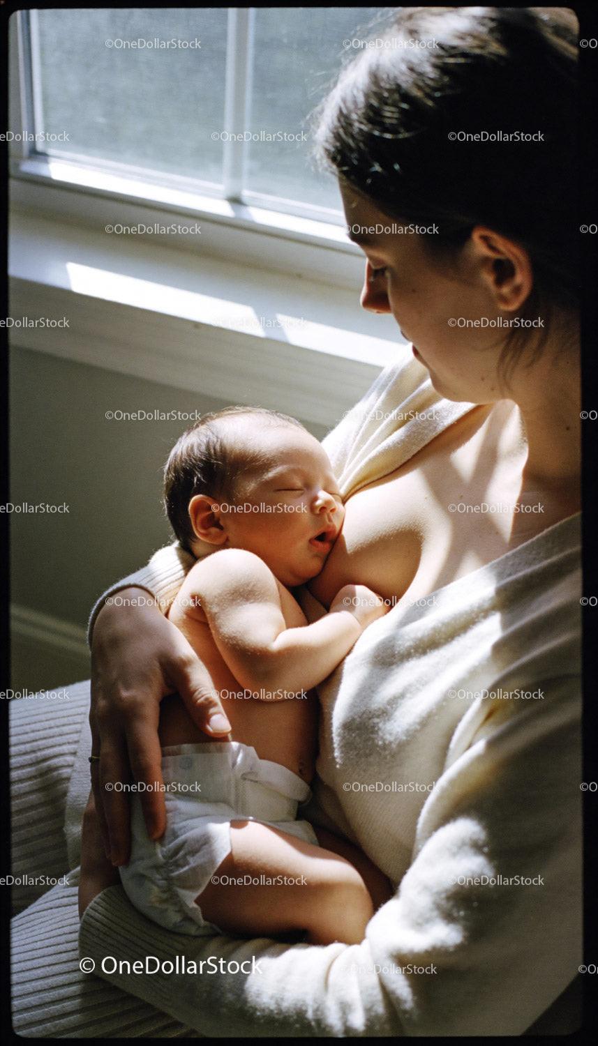 Mother Tenderly Breastfeeding Newborn by Window Light