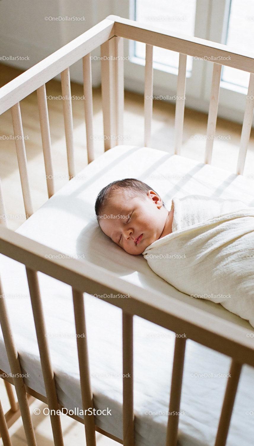 Newborn baby peacefully sleeping in wooden crib sunlight