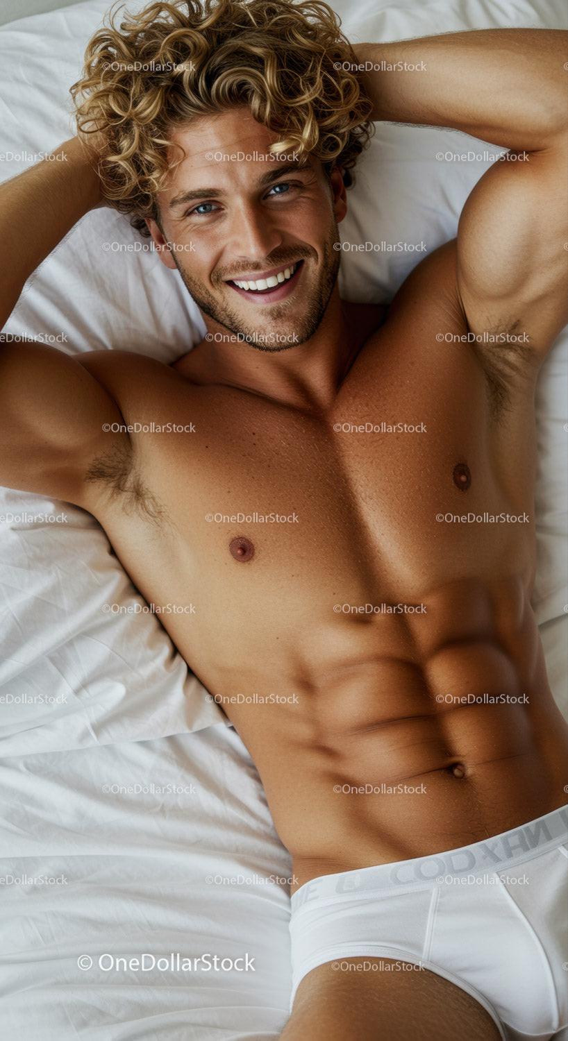 Smiling young man relaxing on bed in white briefs