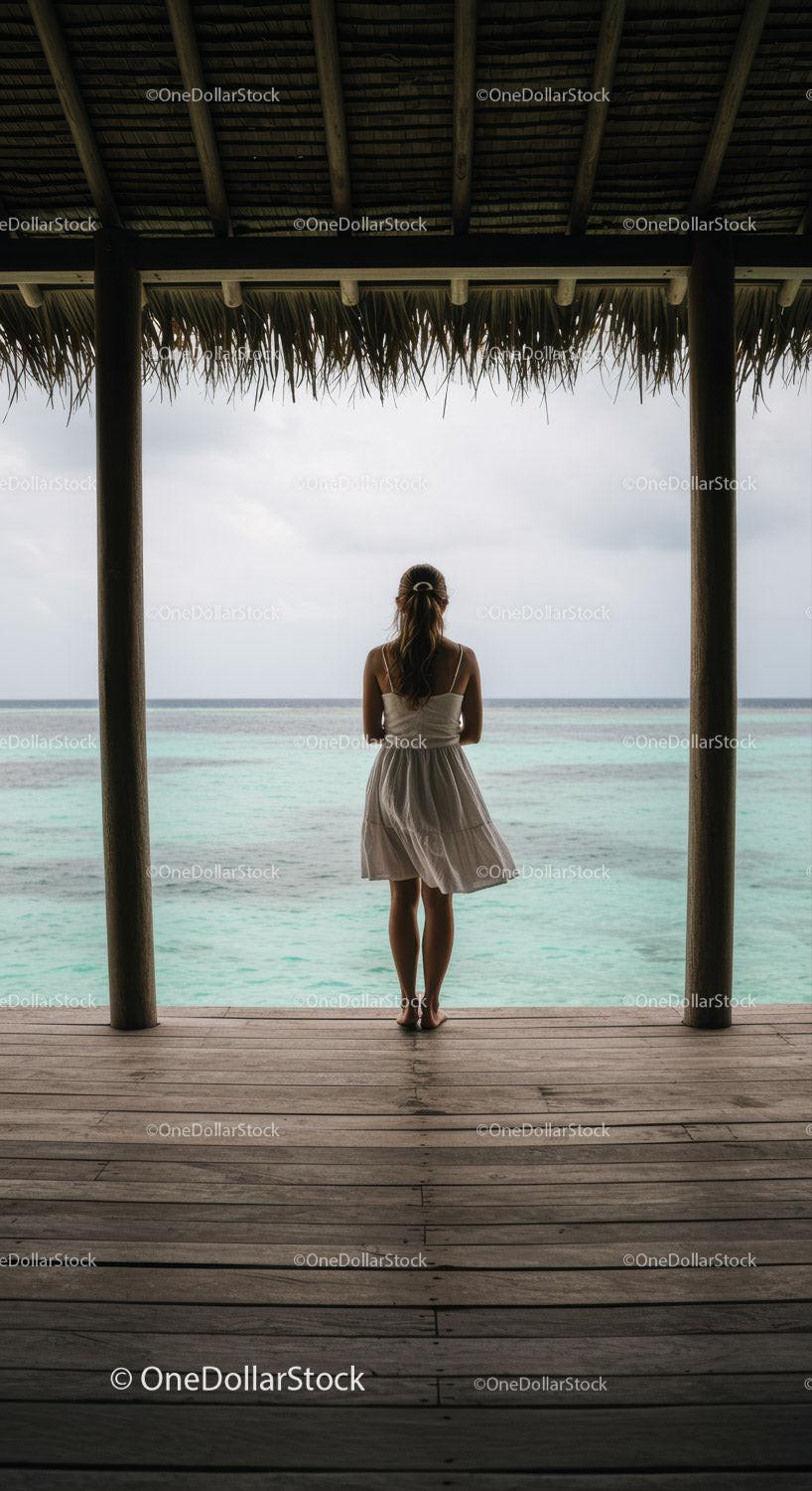 Woman Standing at a Tropical Beach Hut Overlooking Calm Ocean Horizon