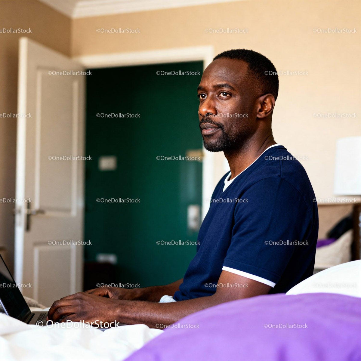 Thoughtful man working on laptop in cozy bedroom