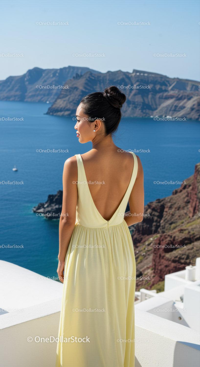 Woman in yellow dress gazing at coastal cliffs