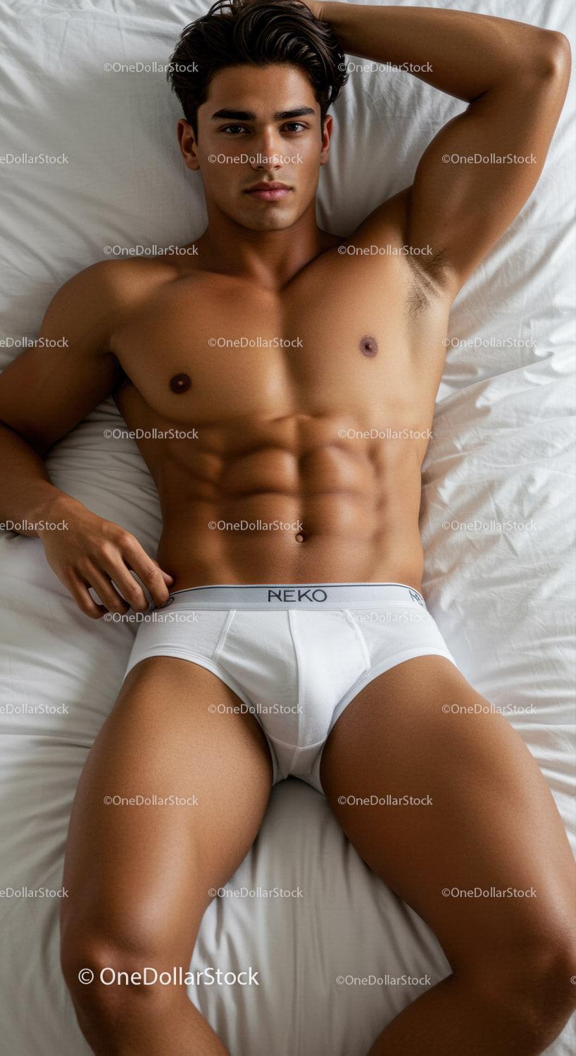 Fit young man relaxing in white briefs on bed