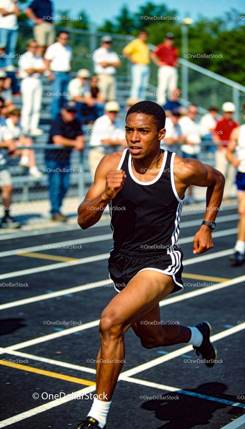 Focused male sprinter racing on outdoor track