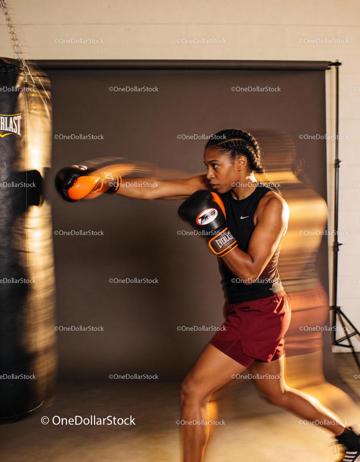 Focused woman training with boxing gloves and punching bag