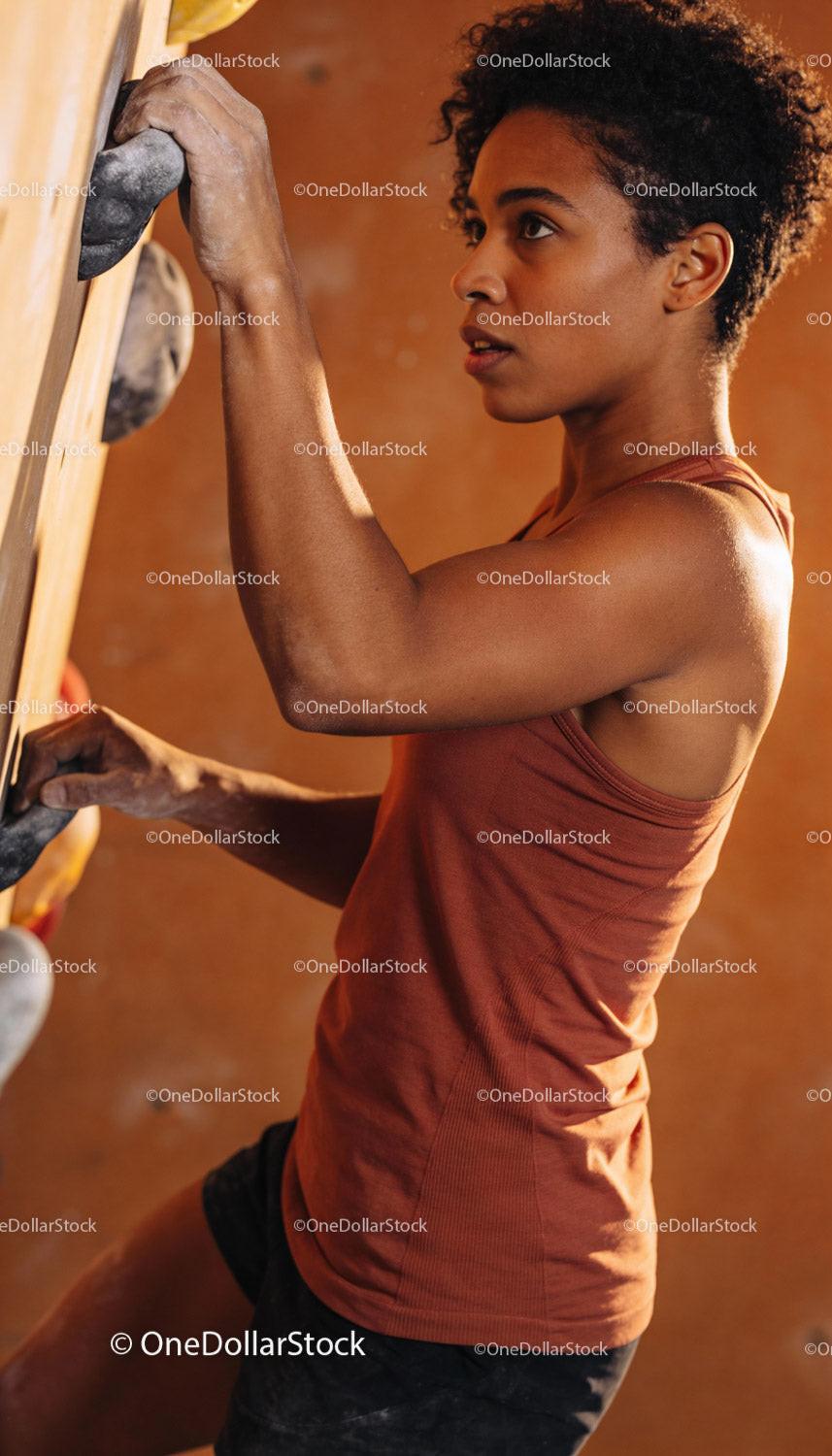 Focused young woman climbing indoor bouldering wall