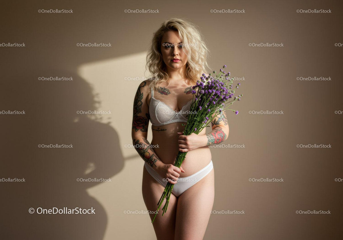 Tattooed Woman Holding Purple Flowers in Lingerie on Minimalist Background