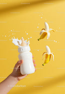 Baby bottle with splash and peeled bananas on yellow background