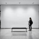 Woman walking past empty bench in modern gallery space