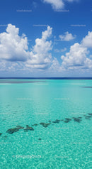 Bright Blue Sky Over Turquoise Ocean with Fluffy White Clouds