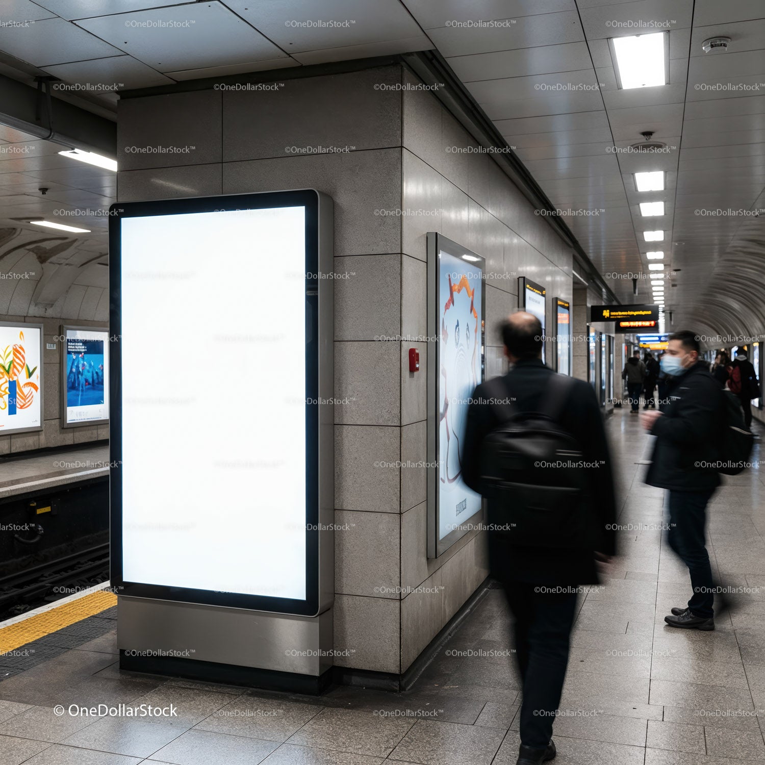 Commuters walking past blank billboard in urban subway station