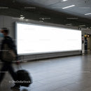 Traveler walking past large blank airport billboard