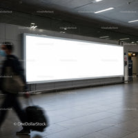 Traveler walking past large blank airport billboard