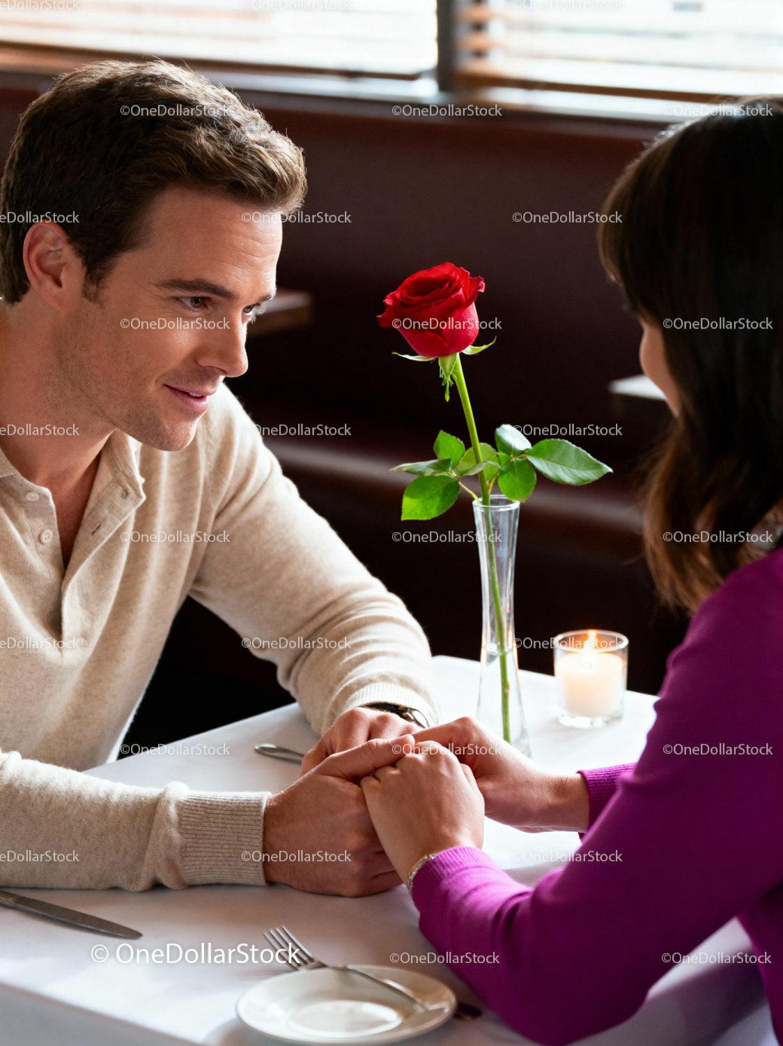 Couple Sharing Intimate Moment with Rose at Romantic Dinner