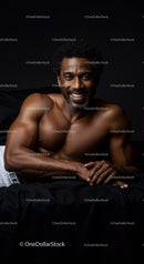 Smiling muscular man lying on black bed in dark room