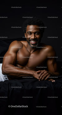 Smiling muscular man lying on black bed in dark room