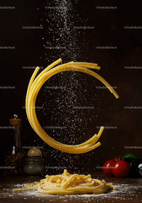Curved raw pasta with falling flour and fresh vegetables