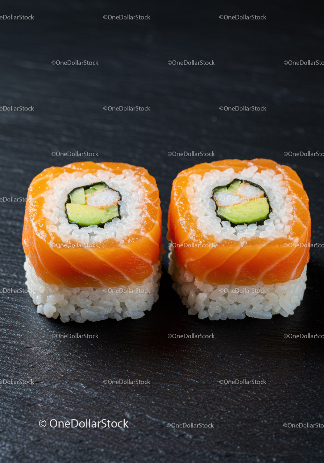Two salmon avocado sushi rolls on dark surface